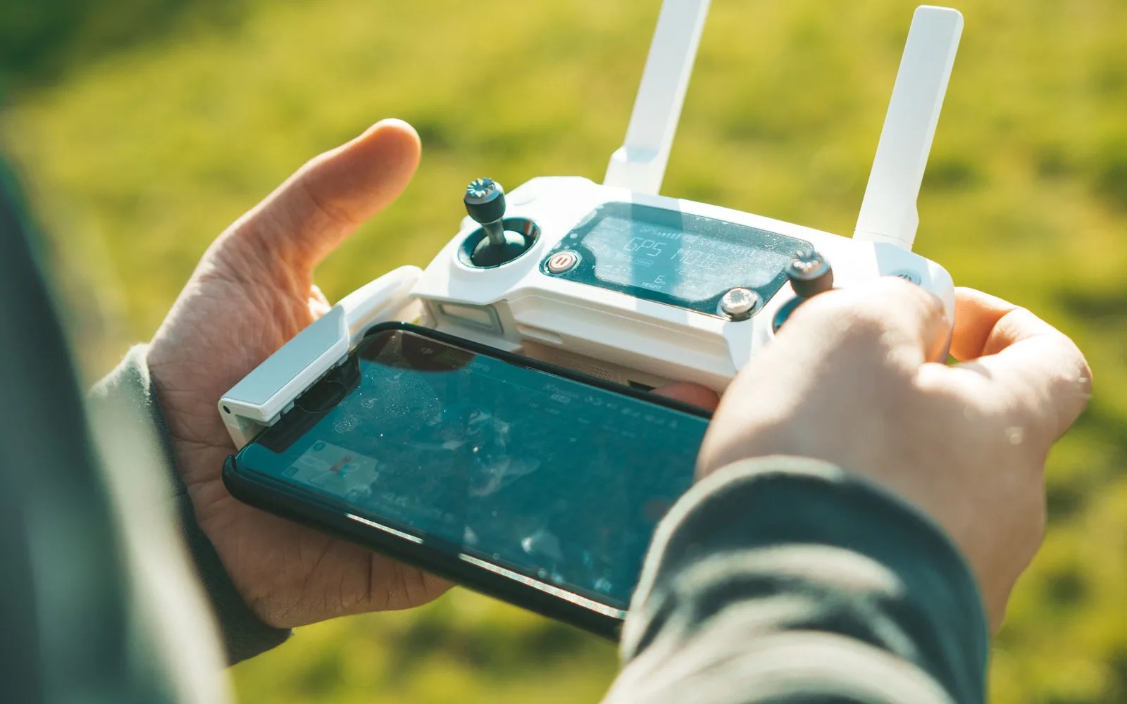 Manos operando un control remoto de dron a la luz del sol