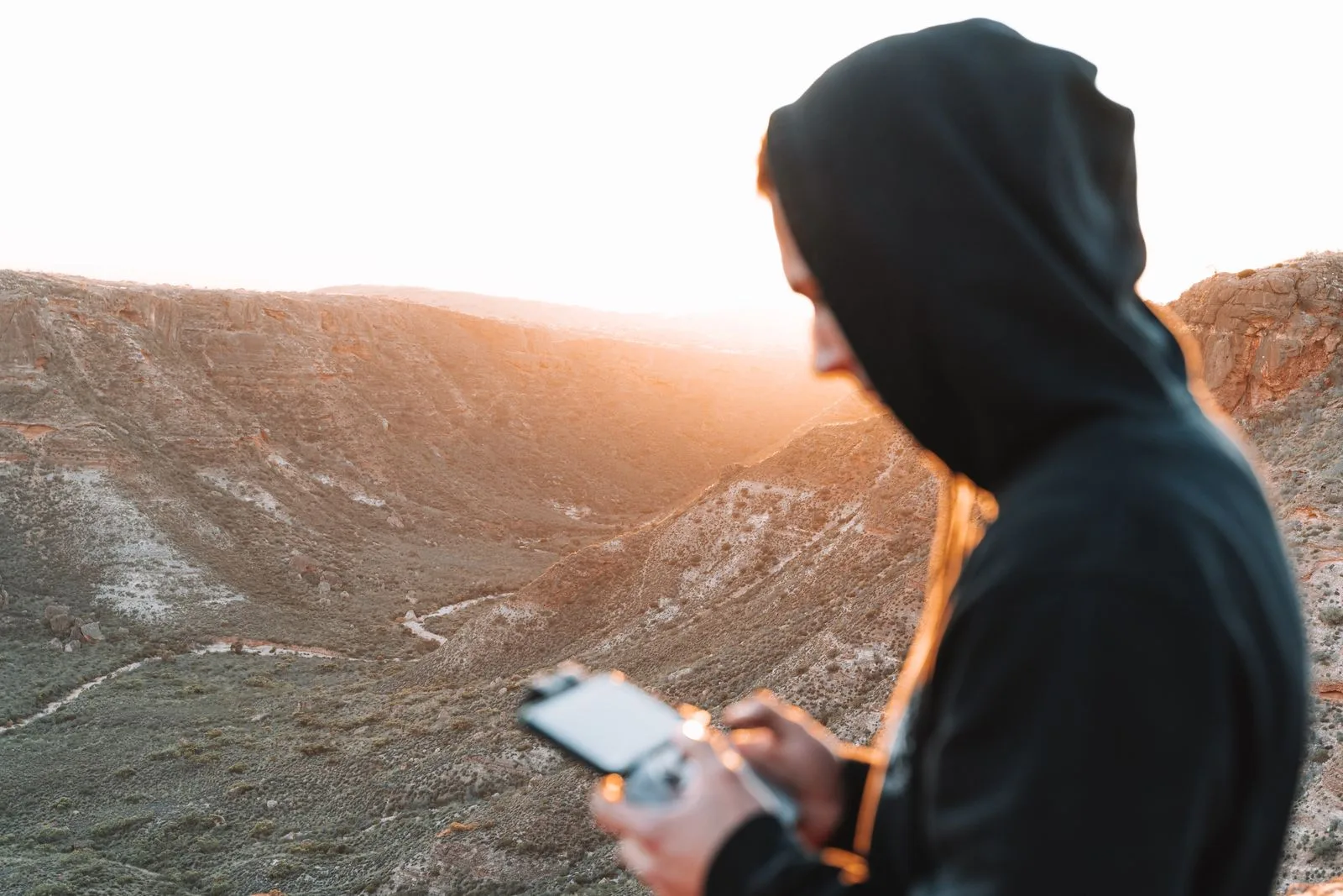 Piloto operando un dron al atardecer en un entorno de cañón