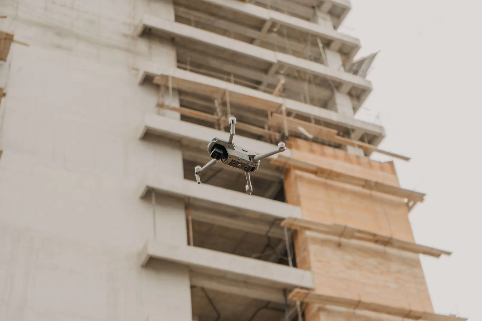 Dron en vuelo visto desde abajo, cerca de una construcción en zona urbana