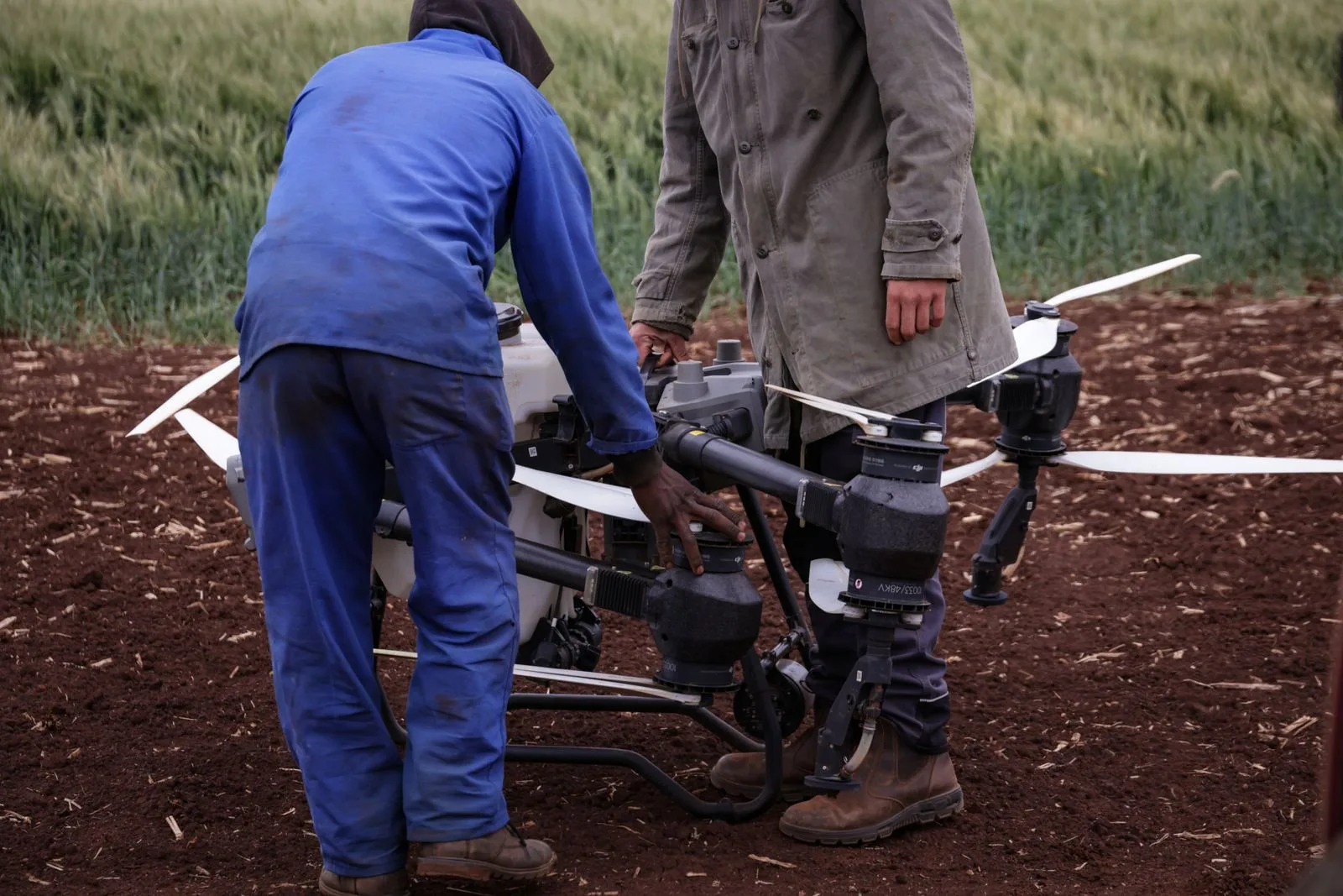 Dos operadores preparando un dron agrícola en el campo